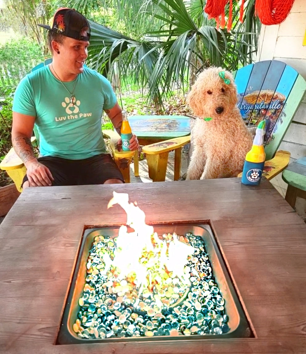 Man wearing a heather seagreen t-shirt with the Luv the Paw logo sitting next to his doodle dog.