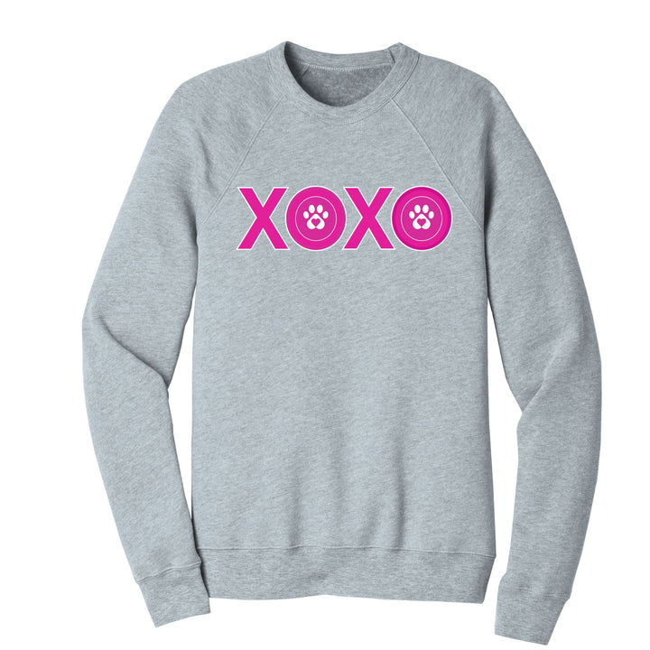 An athletic heather crewneck with XOXO in bright pink text. The 'O" has a paw print in the middle.