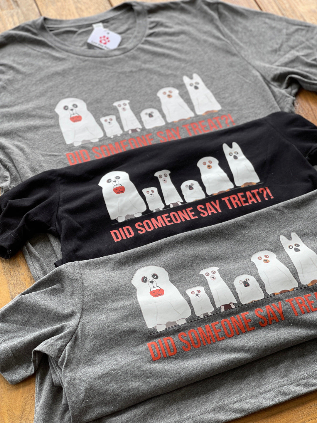3 Halloween t-shirts with dogs in ghost costumes in flat lay. 